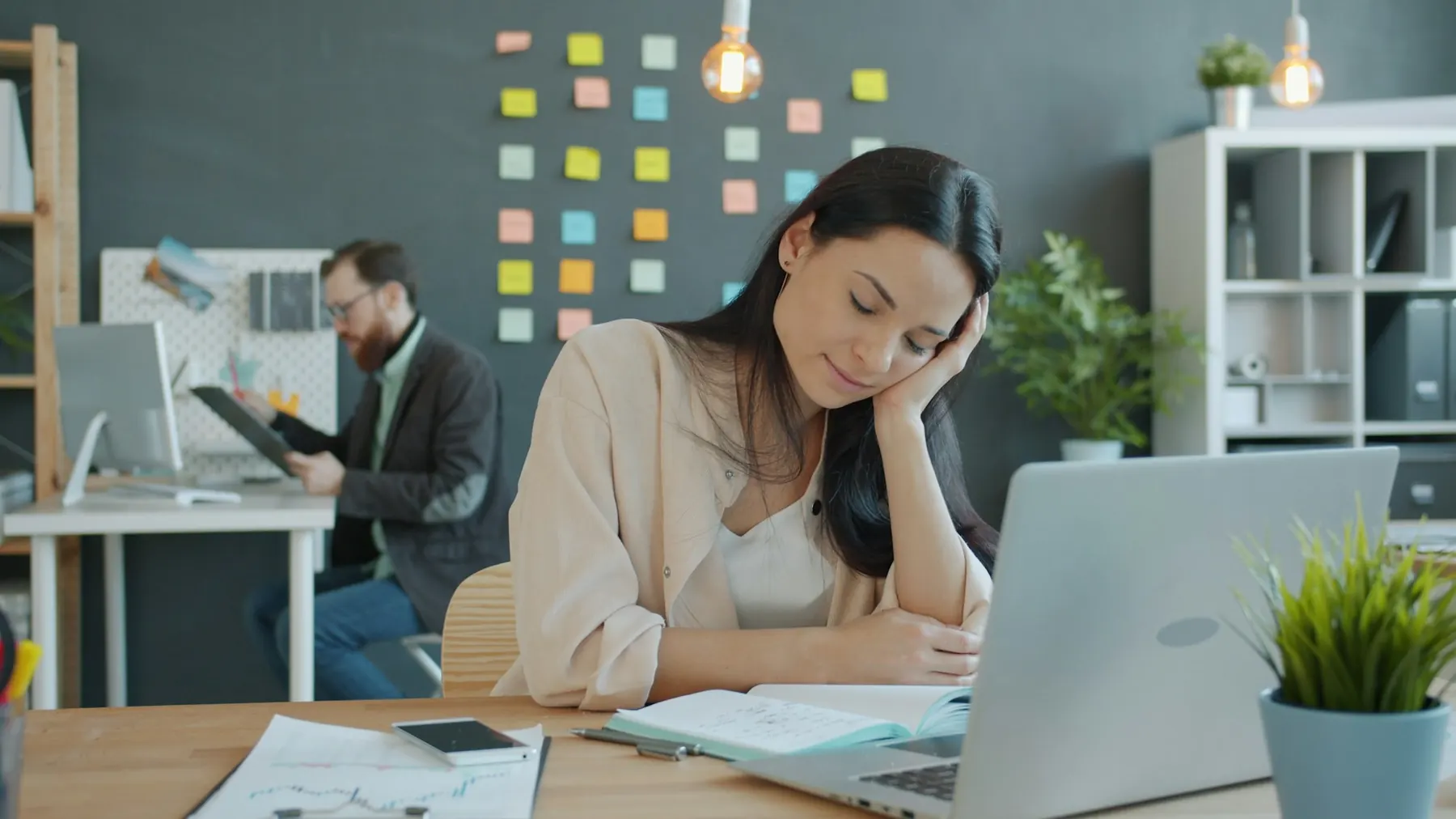 A tired woman resting her head on her hand at her desk